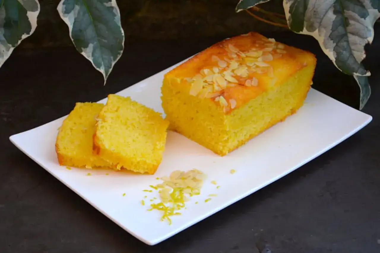 Un délicieux gâteau jaune, garni d'amandes effilées et de zeste de citron, prêt à être dégusté. Une recette de gâteau simple et savoureuse.