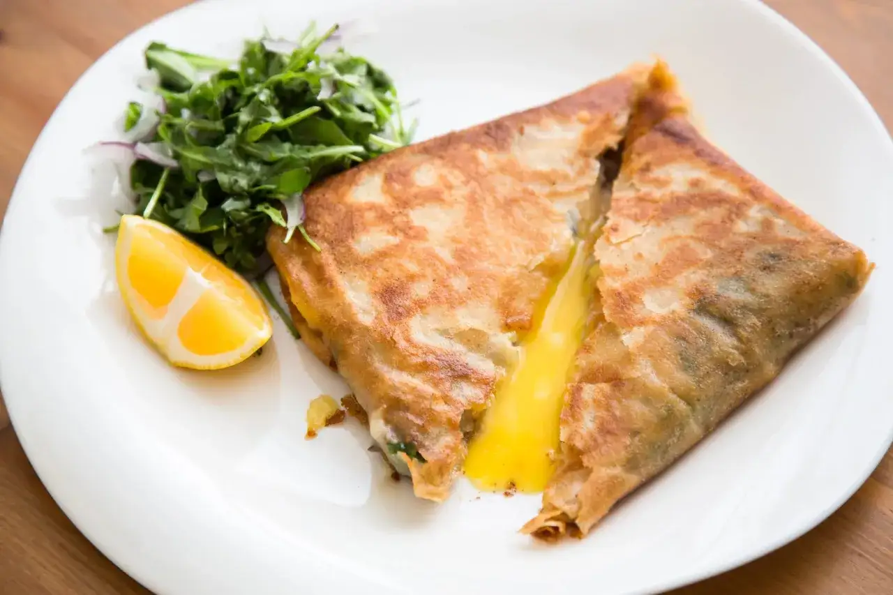 Un délicieux brick au thon, doré et croustillant, avec un cœur coulant de fromage. Servi avec une salade verte et un quartier de citron.