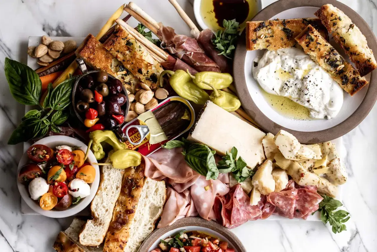 En gener&ouml;s italiensk charkbricka med oliver, tomater, burrata, salami, prosciutto, kron&auml;rtskocka, br&ouml;d och sardiner.