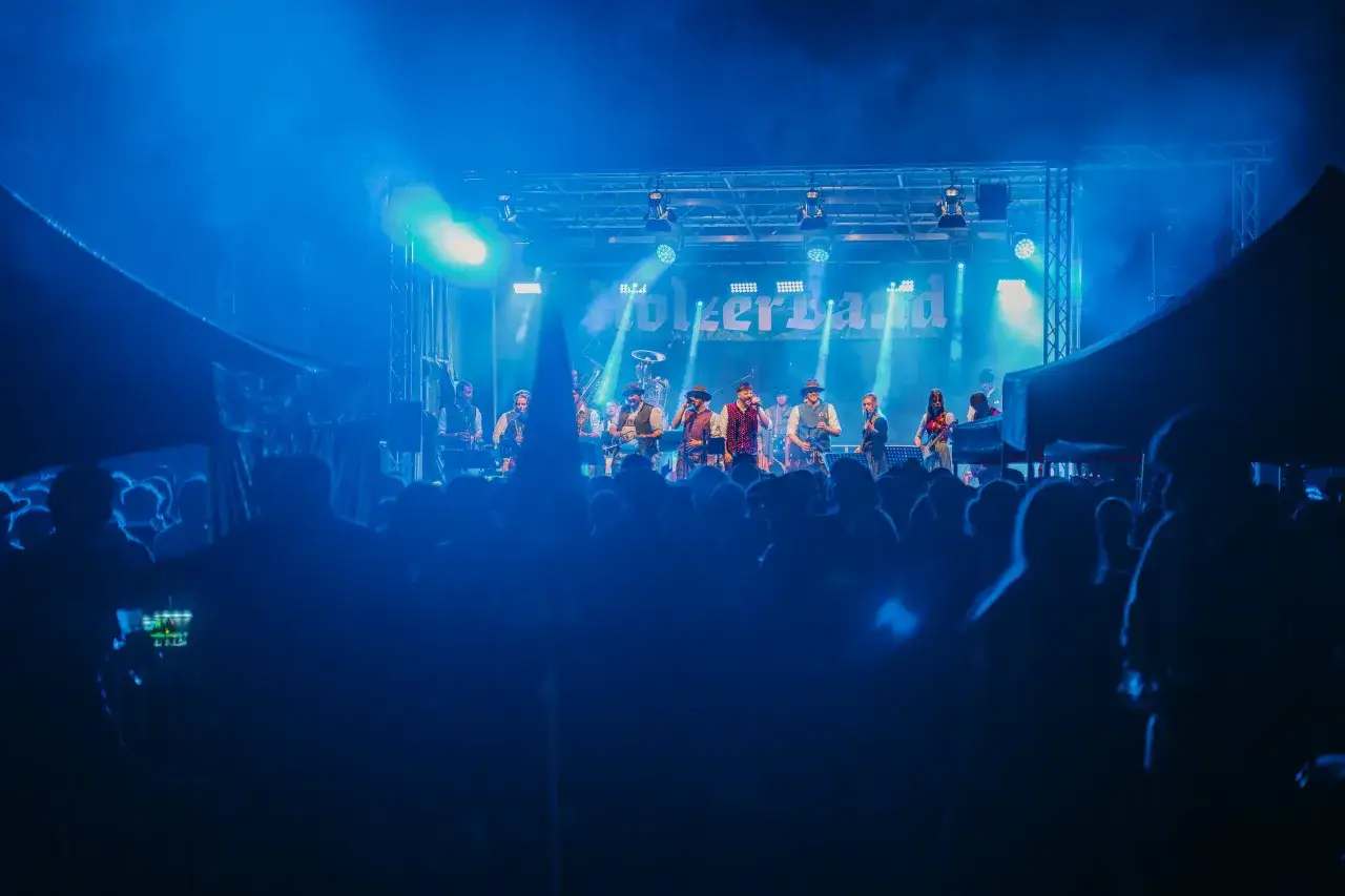La starlight band suona sotto luci blu intense, con il pubblico in silhouette che applaude.
