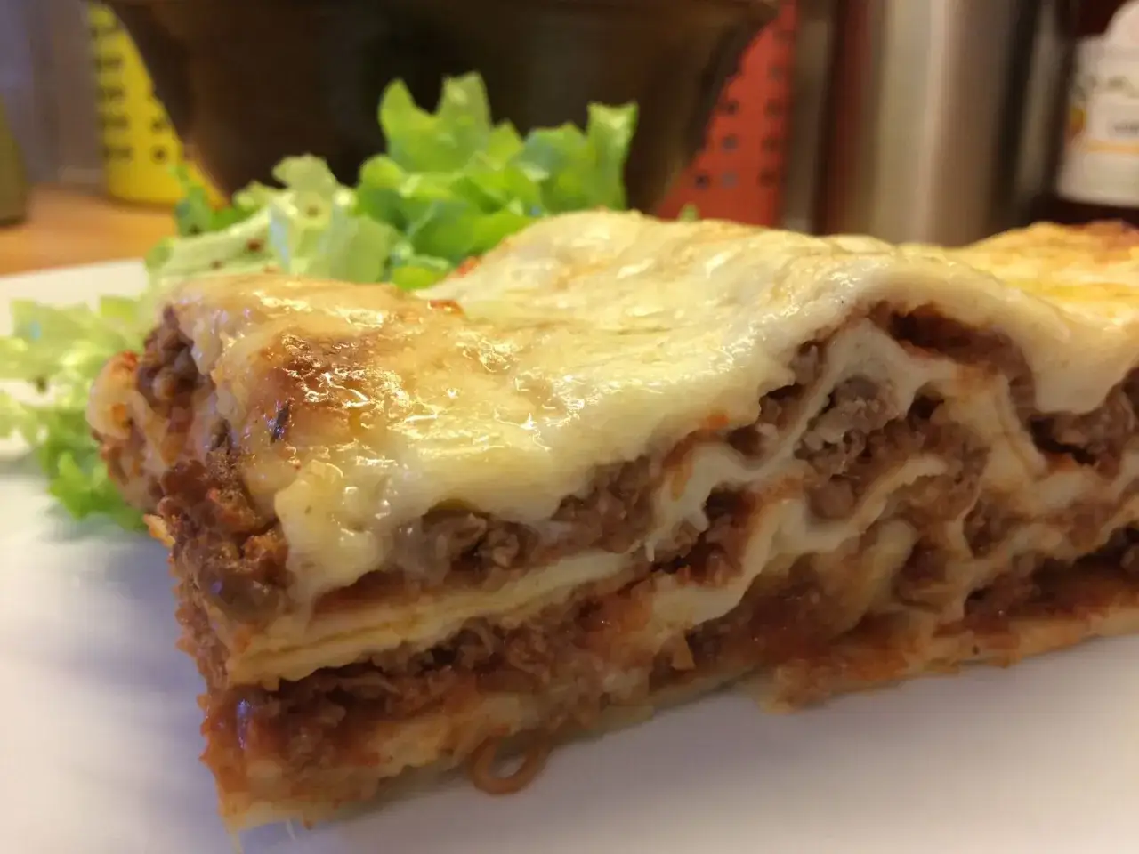 Une part de lasagnes généreuse, prête à rechauffer au four, avec une touche de salade verte.