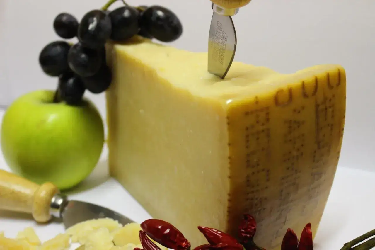 Ein St&uuml;ck Parmigiano Reggiano mit Trauben, Apfel und Chilis. Verschiedene parmesan sorten sind ein Genuss.