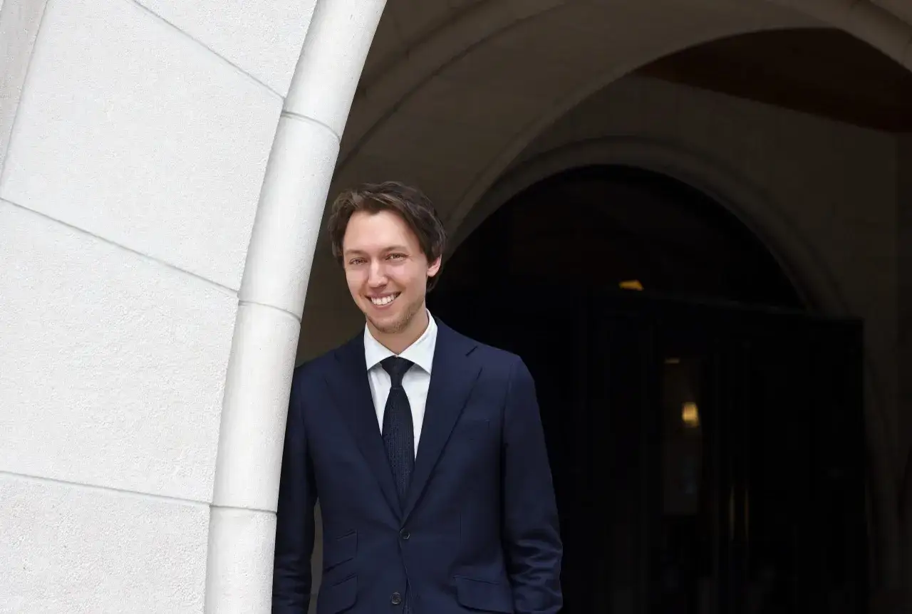 Ung man i m&ouml;rk kostym ler vid en stenb&aring;ge. Han har precis avslutat sin advokatutbildning och ser fram emot framtiden.