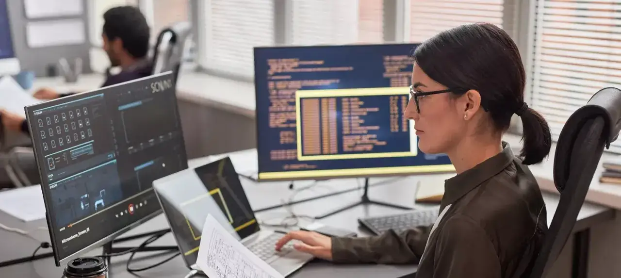 Frau arbeitet an Computern mit Code. Sie ist Teil eines Teams, das an zukunftsorientierten Berufen arbeitet.