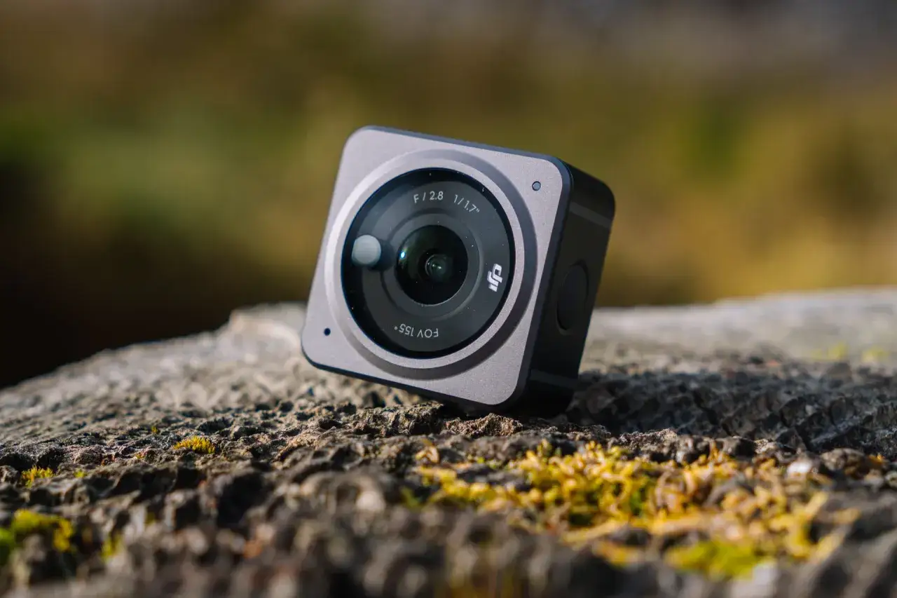 Kompaktowa kamera insta360 go 3s leży na pniu drzewa, gotowa do uchwycenia przygód.