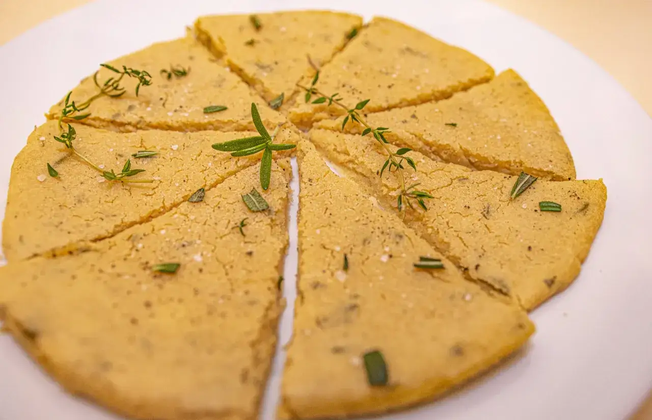 Kichererbsenmehl Rezepte: goldgelbe, in Stücke geschnittene Socca, garniert mit frischen Kräutern und Meersalz.