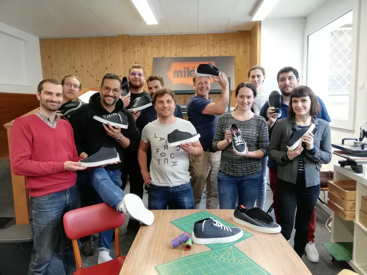 L'équipe célèbre sa journée du personnel en montrant fièrement les chaussures qu'ils ont fabriquées.