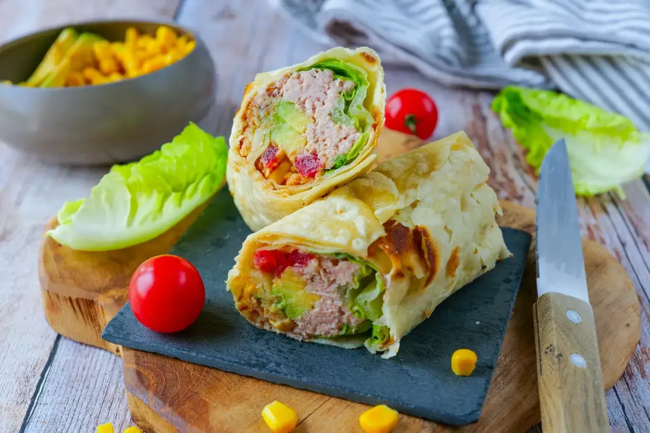 Un délicieux wrap thon garni d'avocat, de tomates et de laitue, prêt à être dégusté.