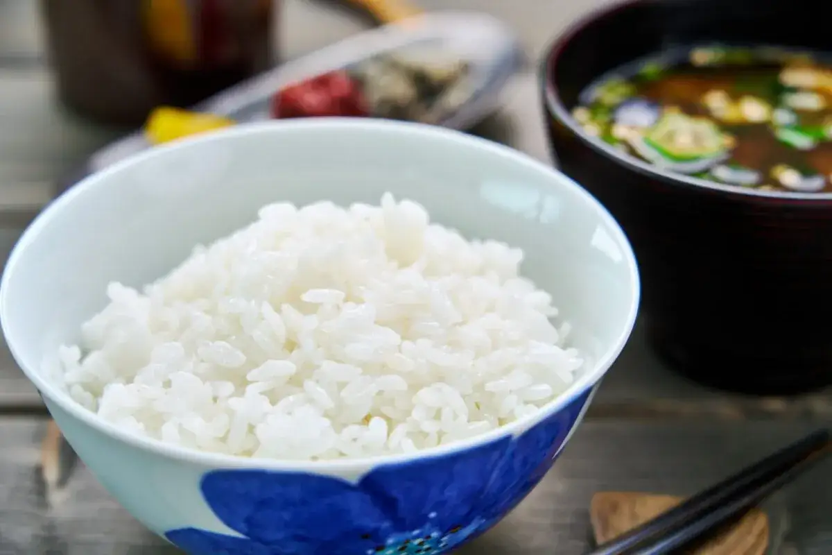 En skål med fluffigt sushi ris, redo att serveras med misosoppa och ätpinnar.