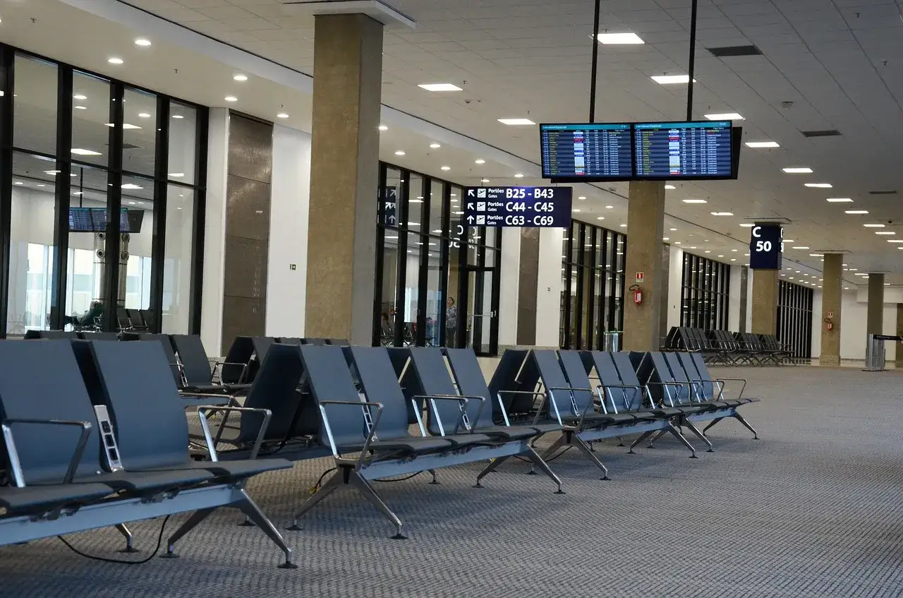 Puste krzesła czekają na pasażerów na lotnisku Bydgoszcz przylot. Tablice informacyjne pokazują bramki.