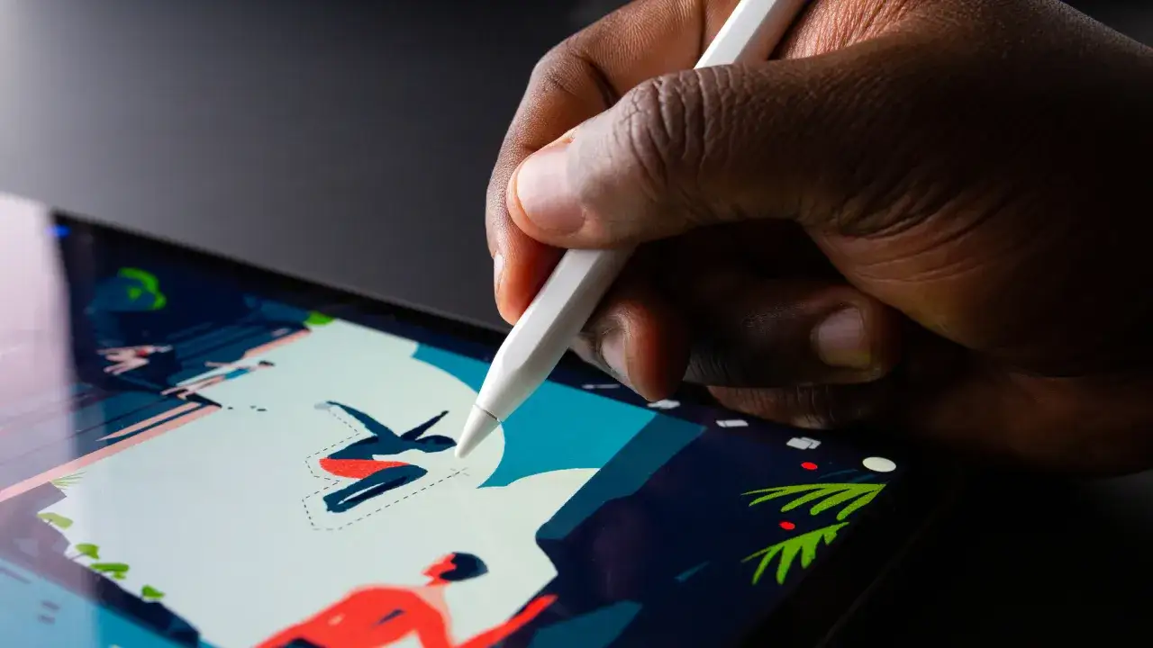 A hand uses a stylus on a tablet, demonstrating how to use Procreate to create vibrant digital art.