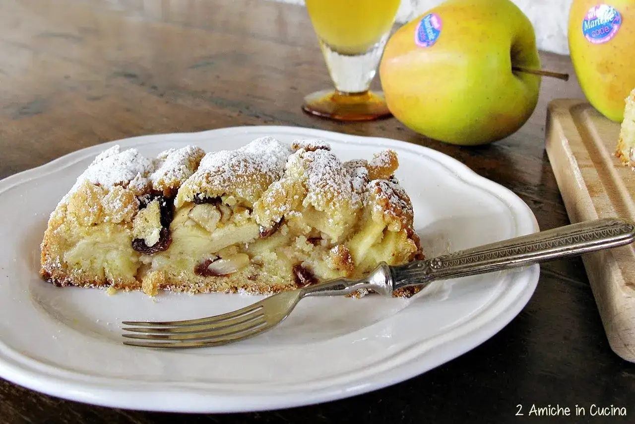 Fetta di strudel con pasta frolla, mele, uvetta e mandorle, spolverata di zucchero a velo.