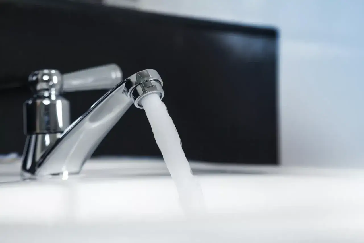 Un robinet chromé verse un jet d'eau froide puissant, signe de plus de pression eau froide sur un seul robinet.