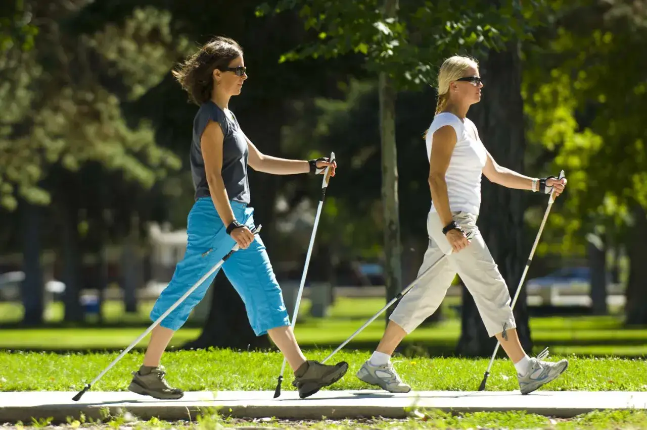 Dwie kobiety uprawiające nordic walking, spalając kalorie na świeżym powietrzu.