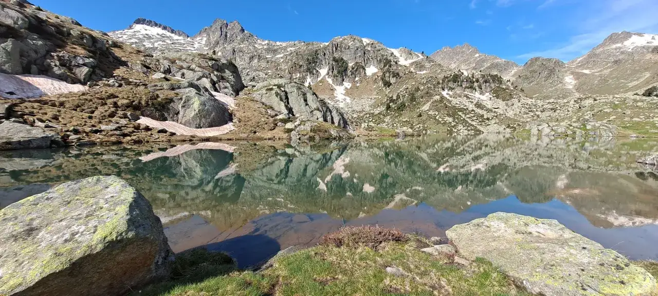 Reflejo perfecto de montañas nevadas en el sereno lago de el cinque llac.