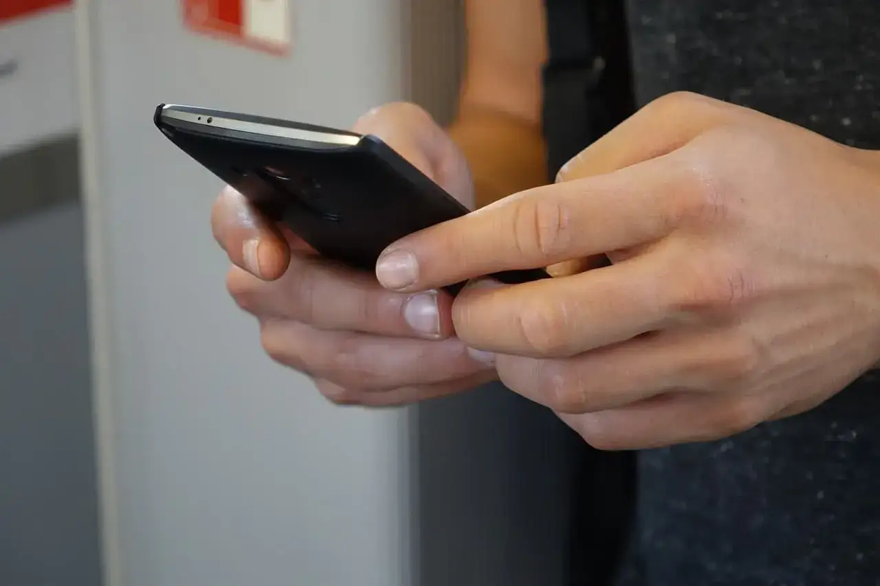 Dłonie trzymające smartfon, być może w trakcie czytania artykułu 190a.