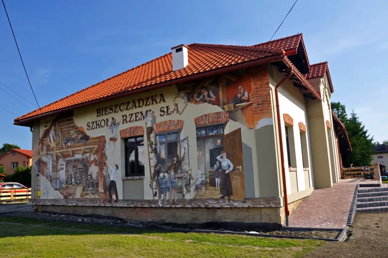 Mural Bieszczadzka Szkoła Rzemiosła przedstawia sceny z życia dawnych rzemieślników i uczniów.