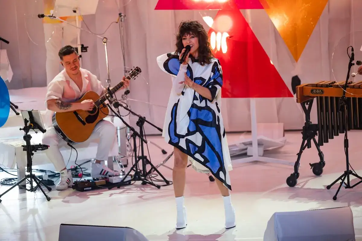 Wokalistka w sukience z geometrycznym wzorem śpiewa na scenie podczas MTV Unplugged Polska. Obok gra gitarzysta.