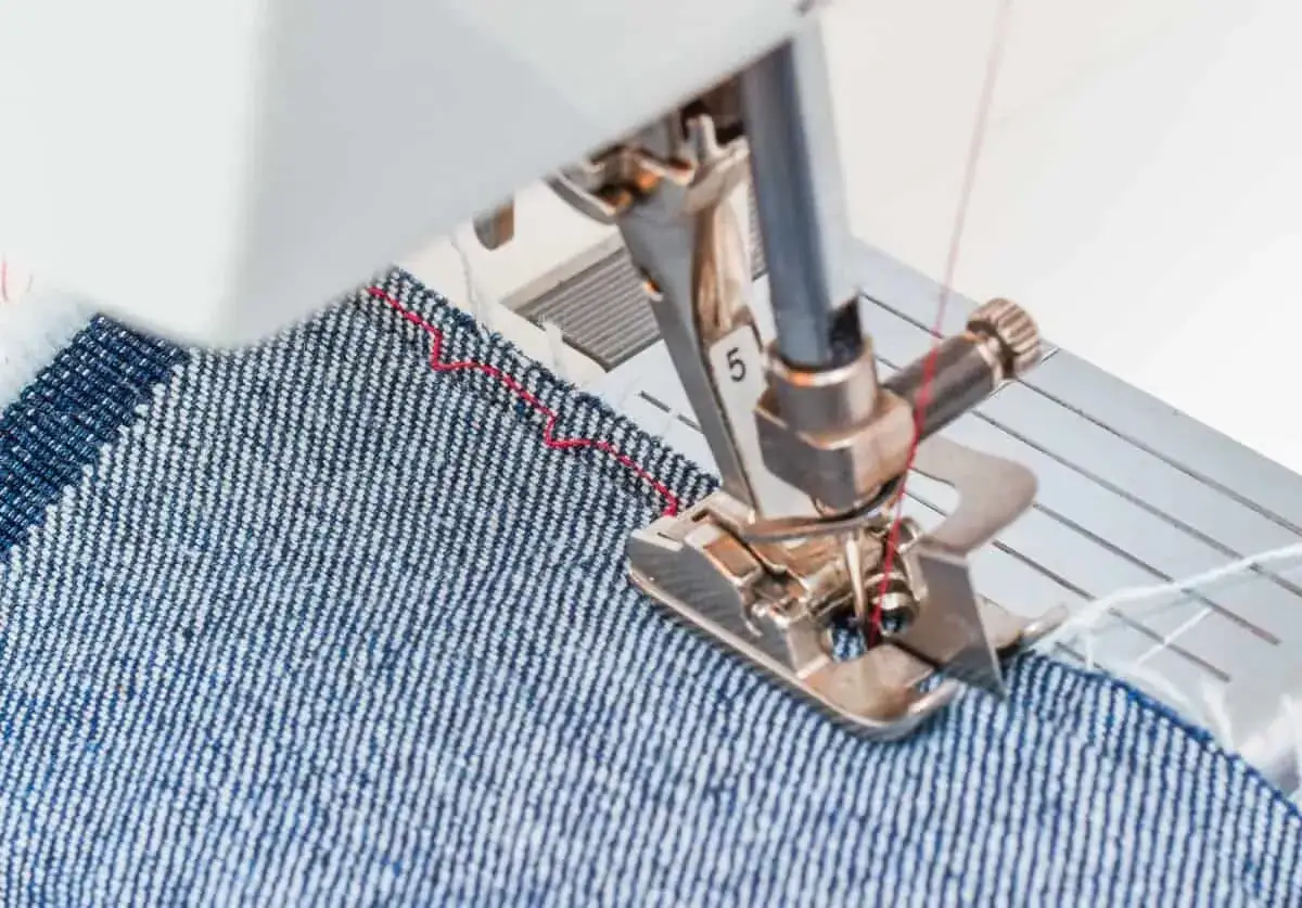 Sewing a blind hem on denim with a blind hem foot. The foot guides the fabric for an almost invisible stitch.