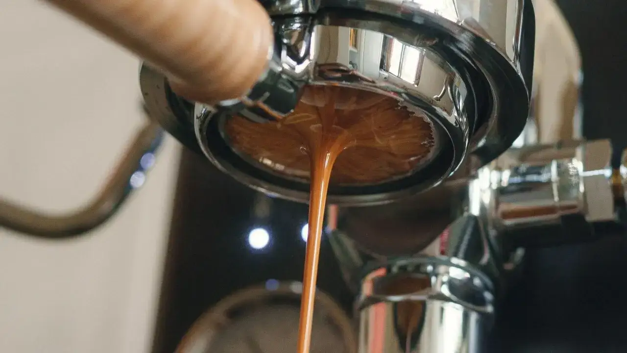 Un filo di caffè scende troppo piano dal portafiltro cromato, creando una crema densa e invitante.