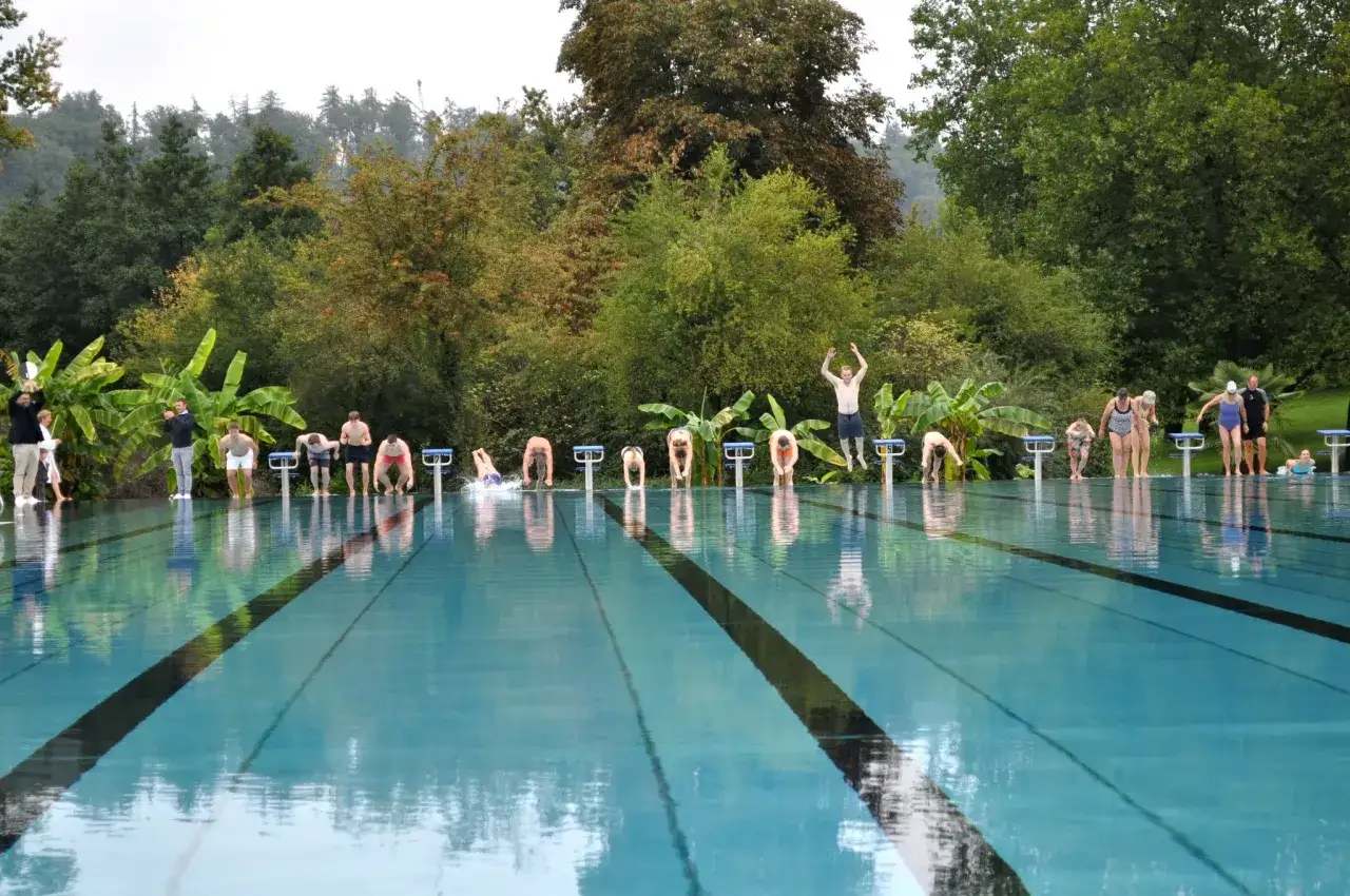 Menschen stehen auf Startbl&ouml;cken im untergruppenbach freibad, bereit zum Sprung ins k&uuml;hle Nass.