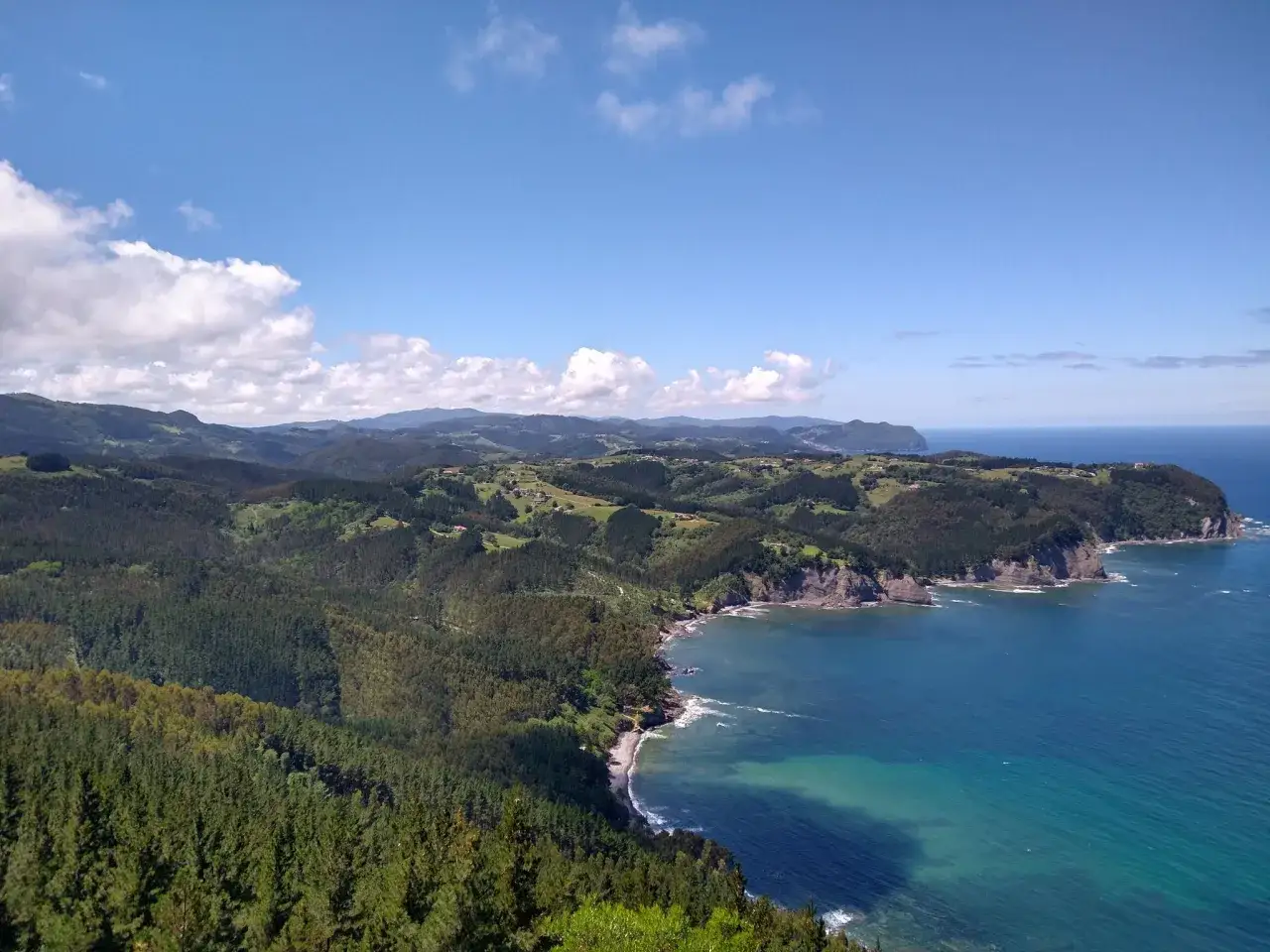 Paisaje costero con bosques frondosos y mar azul. Ideal para explorar las **rutas Lekeitio** y disfrutar de vistas espectaculares.