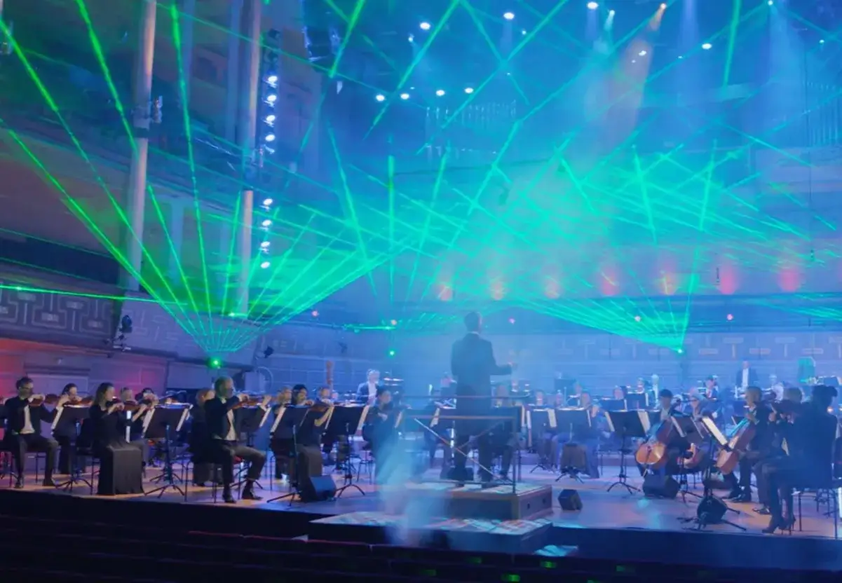 En orkester spelar under en imponerande ljusshow med gröna laserstrålar. En minnesvärd konsert avicii arena.
