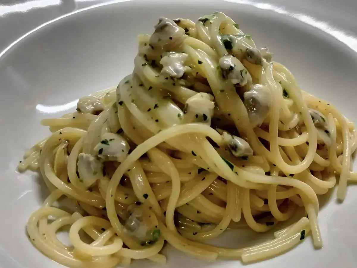 Spaghetti alle vongole cremosi come al ristorante, un piatto invitante con vongole e prezzemolo tritato.