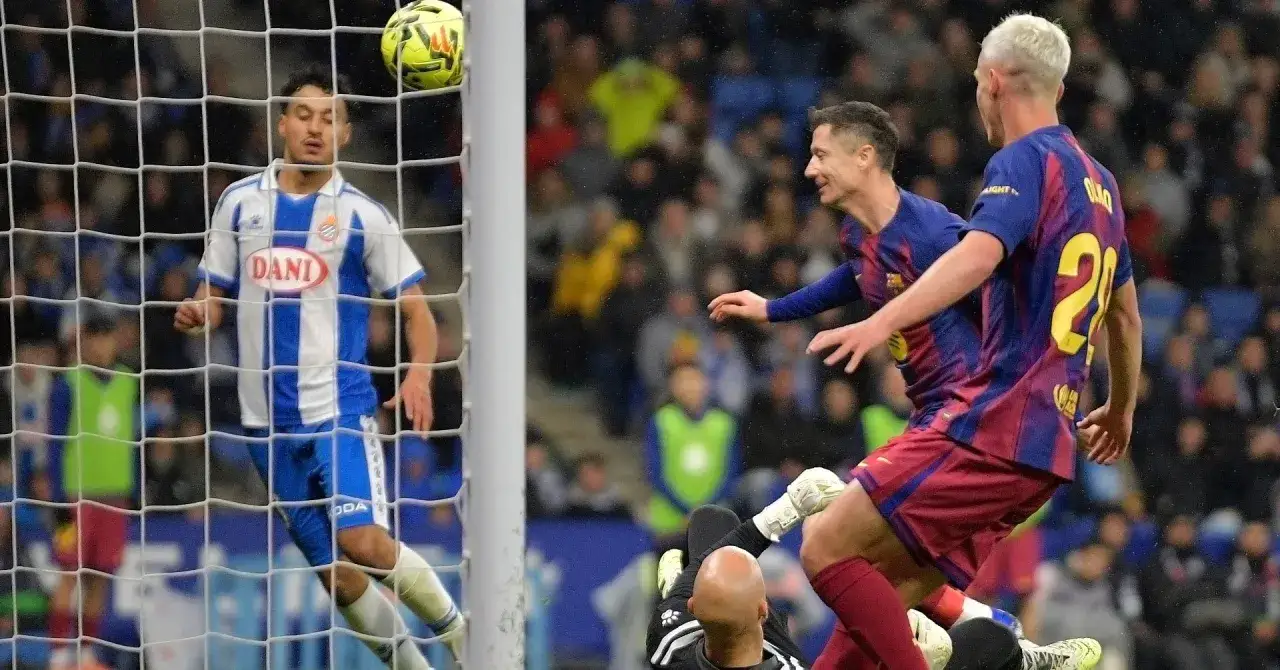 Piłkarze Barcelony, w tym Robert Lewandowski, walczą o piłkę. Bramkarz Espanyolu próbuje interweniować. To obraz z meczu, gdzie rodzą się legendy, jak najlepsi strzelcy Barcelony w historii.