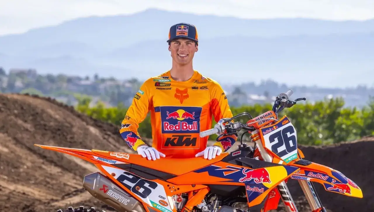 Jorge Prado, piloto de KTM, sonríe junto a su moto de motocross naranja y azul, luciendo su equipo Red Bull.