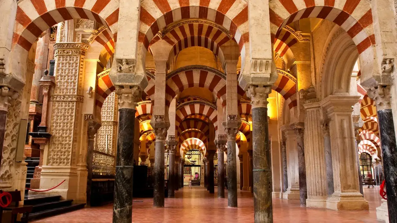 Pasillos de arcos bicolores en la Mezquita-Catedral de Córdoba, un laberinto de piedra y luz.