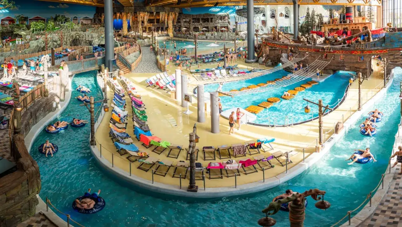 Ein tropischer Tag im Rulantica Wasserpark. Menschen entspannen auf Liegestühlen und treiben auf Schlauchbooten im Wasser.