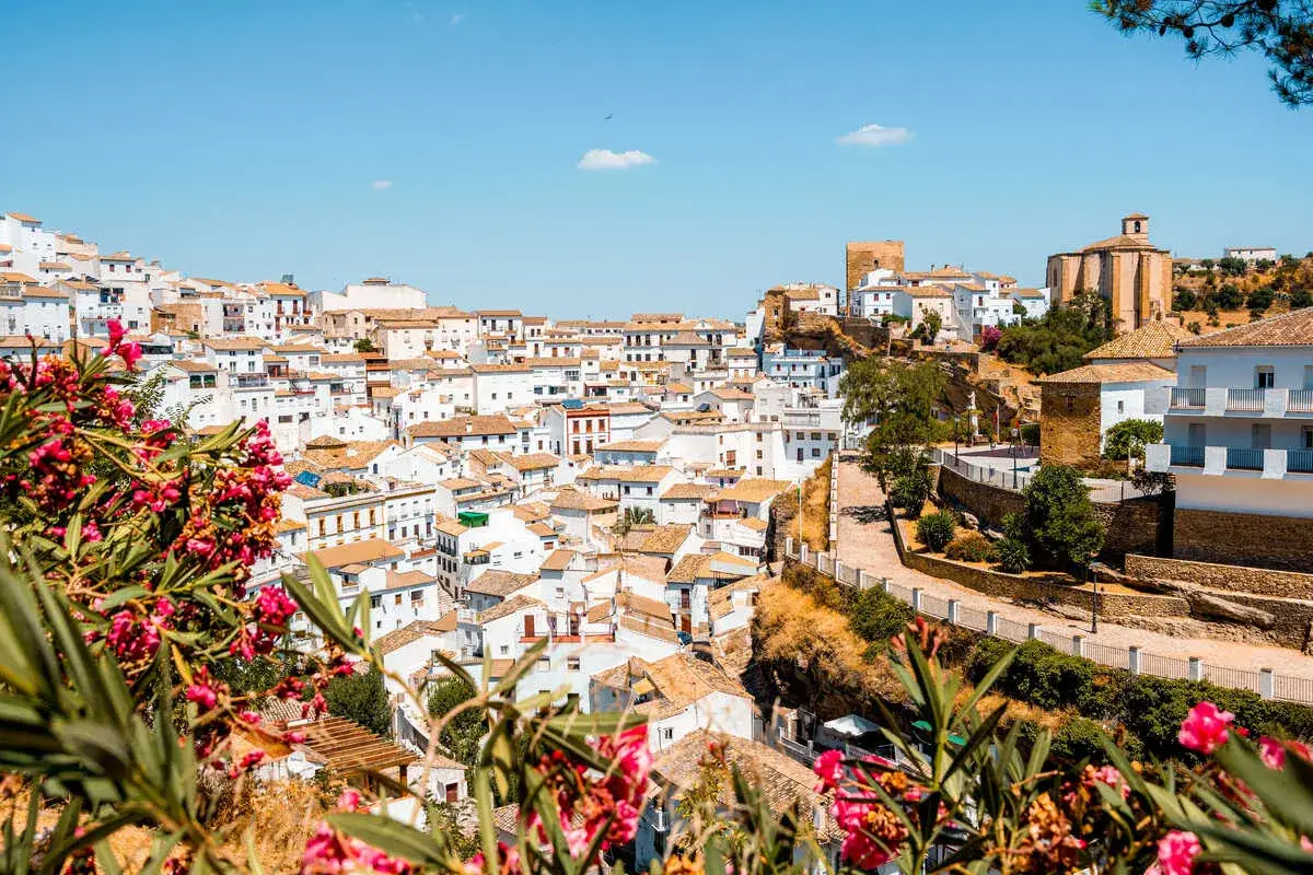 Bunte Bougainvillea blüht vor einer malerischen weißen Stadt in Andalusien. Perfekt für die beste Reisezeit Andalusien!