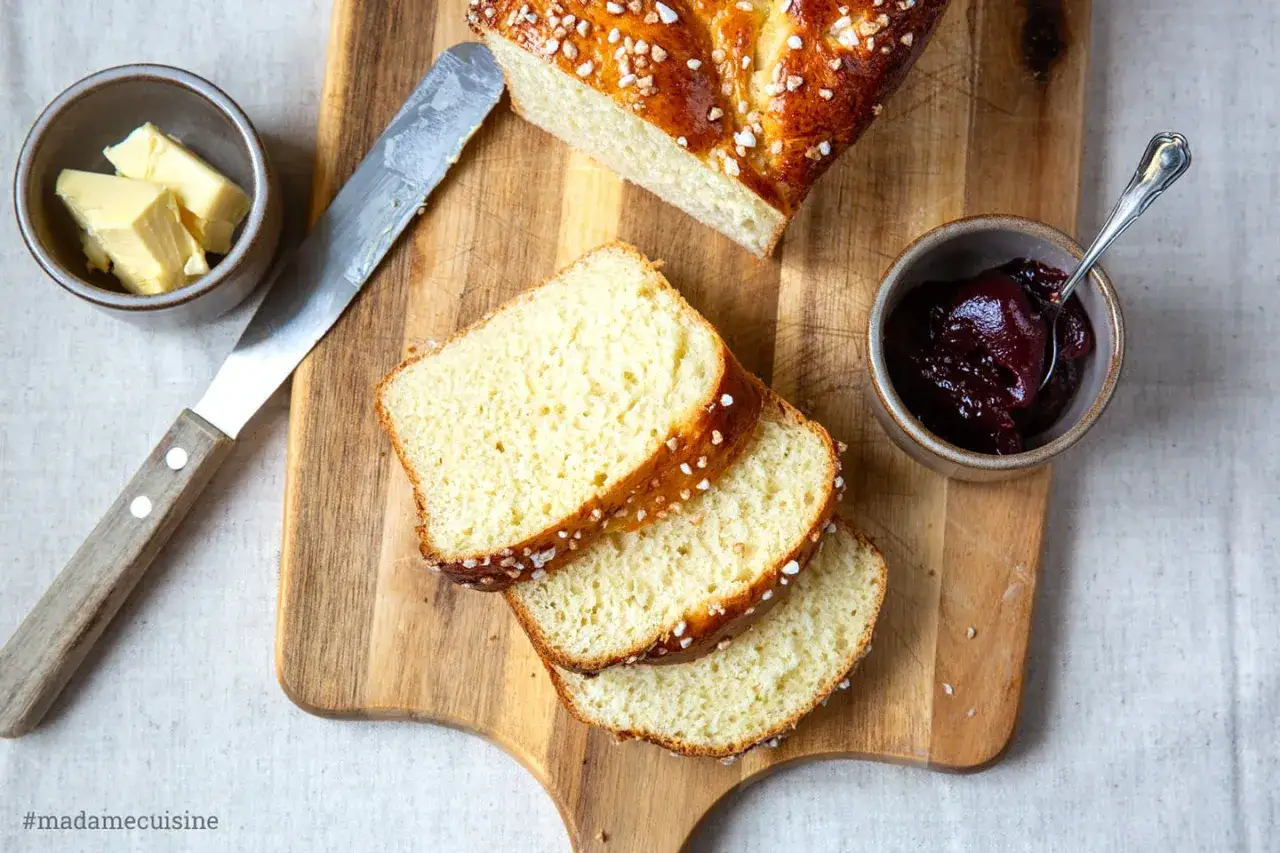 Frisch gebackener Brioche-Zopf mit Butter und Marmelade. Ein köstliches Brioche Rezept für den Sonntagsbrunch.