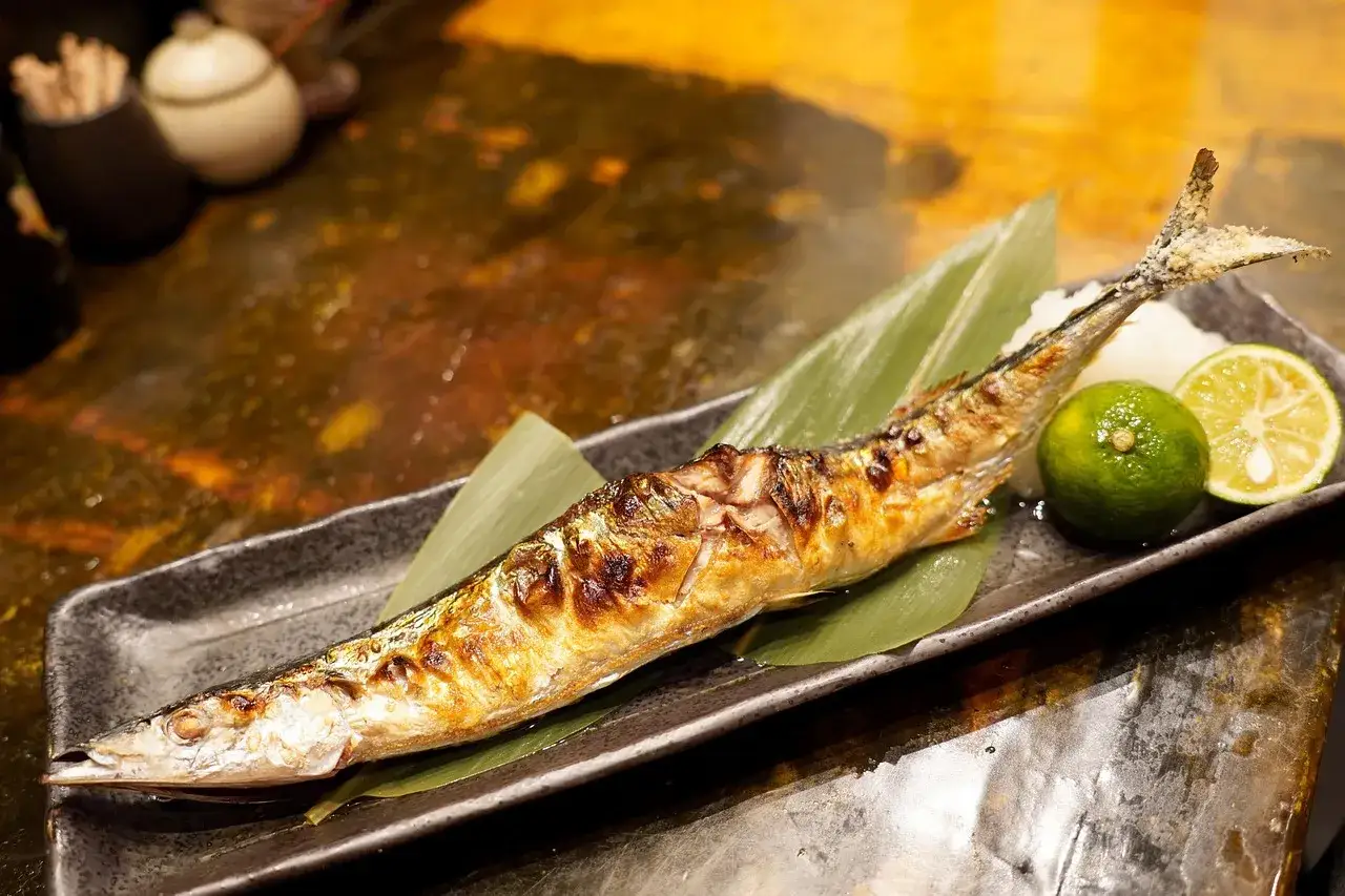 Un saporito luccio alla griglia, servito su una foglia verde con spicchi di lime e un contorno bianco.