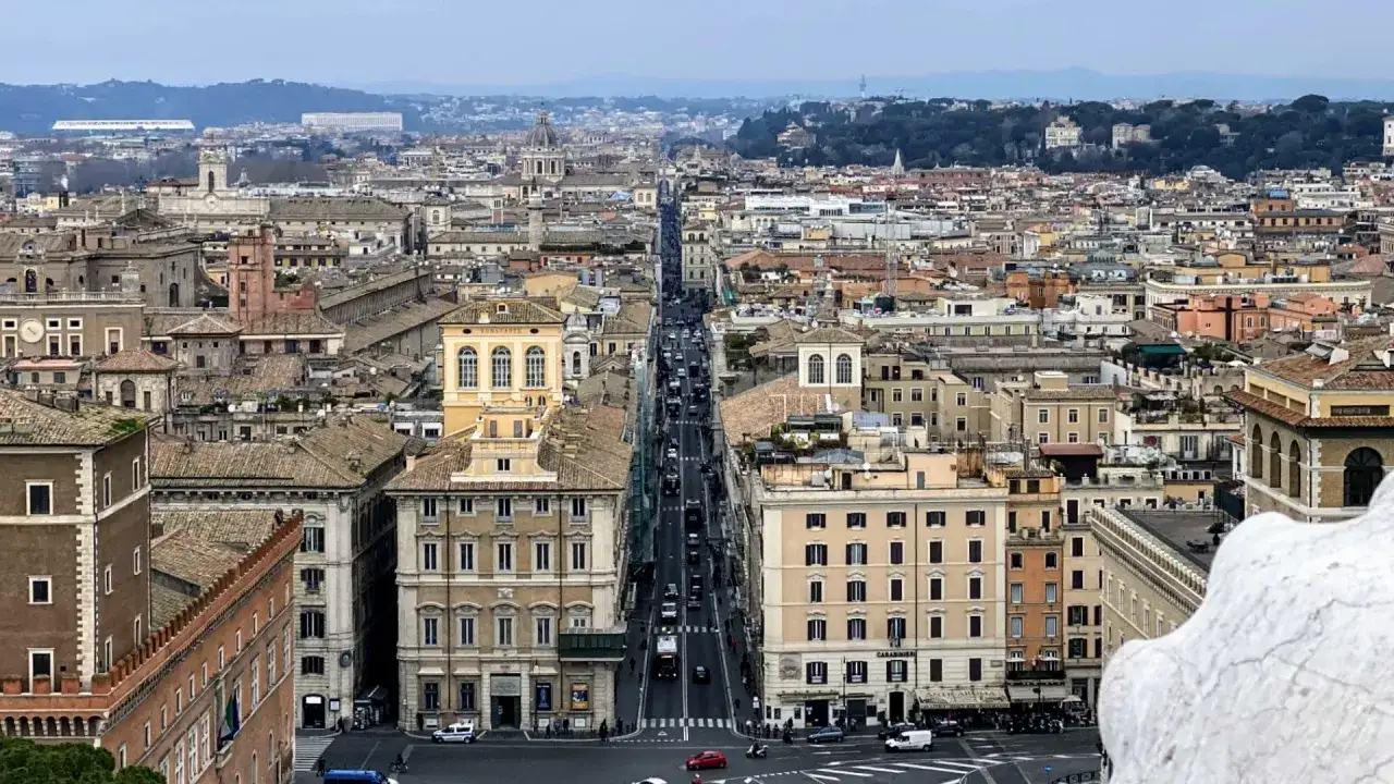 Vista aerea di Roma, con la lunga Via del Corso che si estende tra palazzi storici e traffico.