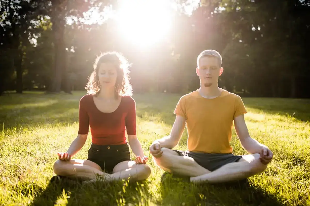 Para medytuje na trawie. Różnica między medytacją chrześcijańską a technikami mindfulness jest subtelna, ale ważna.