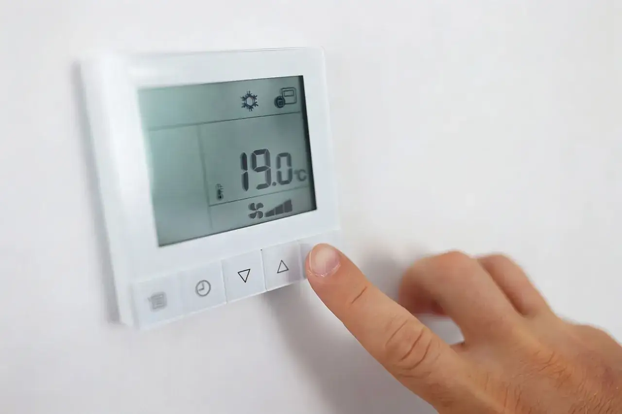 Dito l'indicatore temperatura scaldabagno mostra 19&deg;C, con un dito che preme il pulsante di aumento.