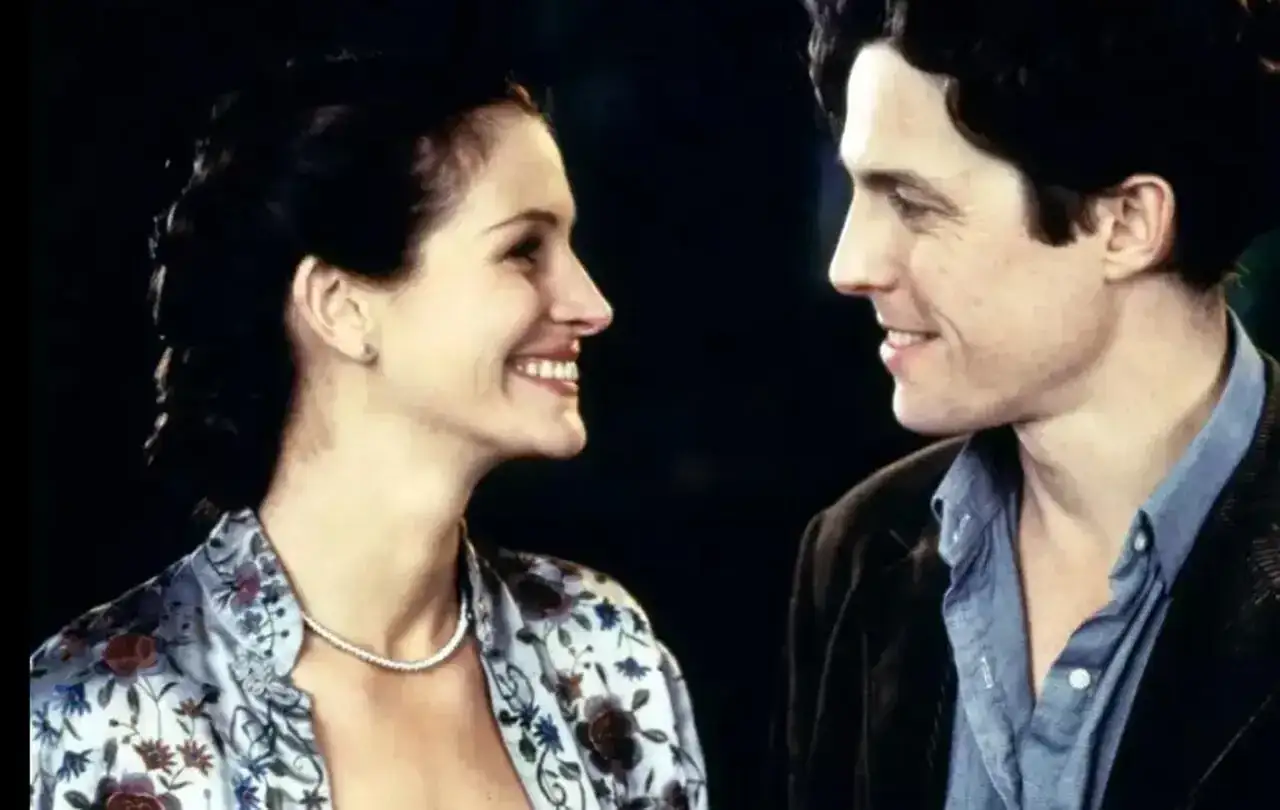 Julia Roberts i Hugh Grant, czyli niezapomniana notting hill obsada, patrzą na siebie z uśmiechem.
