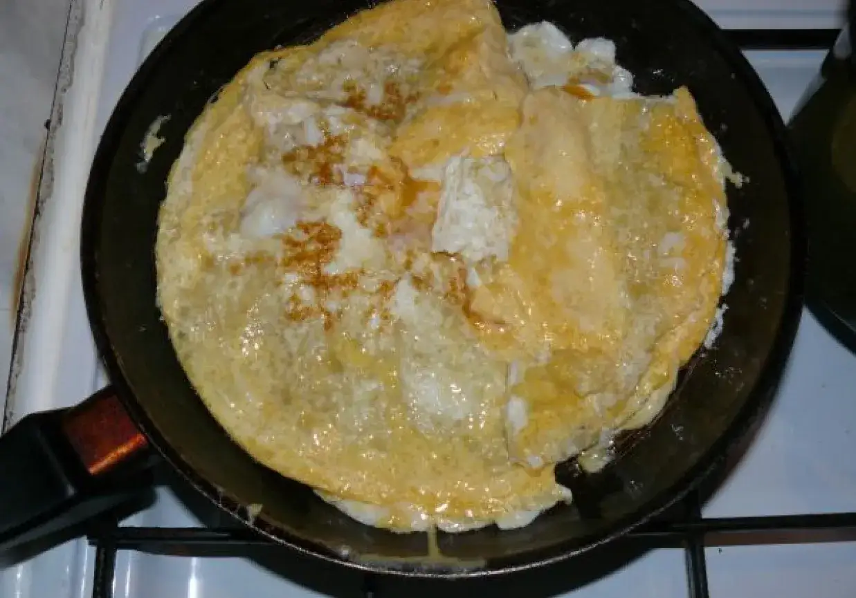 Złocista tortilla z jajkiem smaży się na patelni, tworząc pyszne śniadanie.