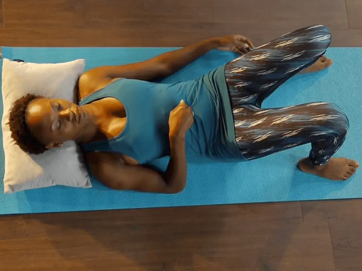 Kvinna p&aring; yogamatta, med b&ouml;jda kn&auml;n och f&ouml;tterna mot varandra, utf&ouml;r ett delade magmuskler test.