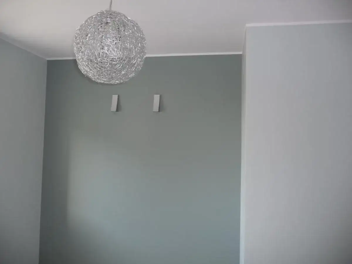 Nowe, jasne wnętrze z nowoczesną lampą. Widać, jak równo odciąć sufit od ściany, tworząc czystą linię.
