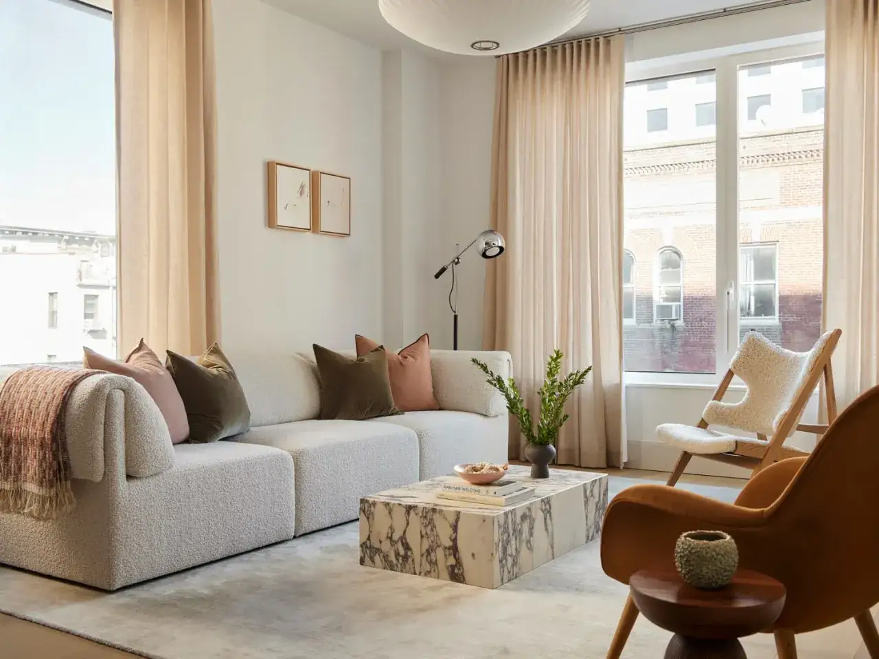 A modern living room with a boucle sofa, marble coffee table, and plush rug. This space offers inspiration on how to choose a rug to complete your decor.
