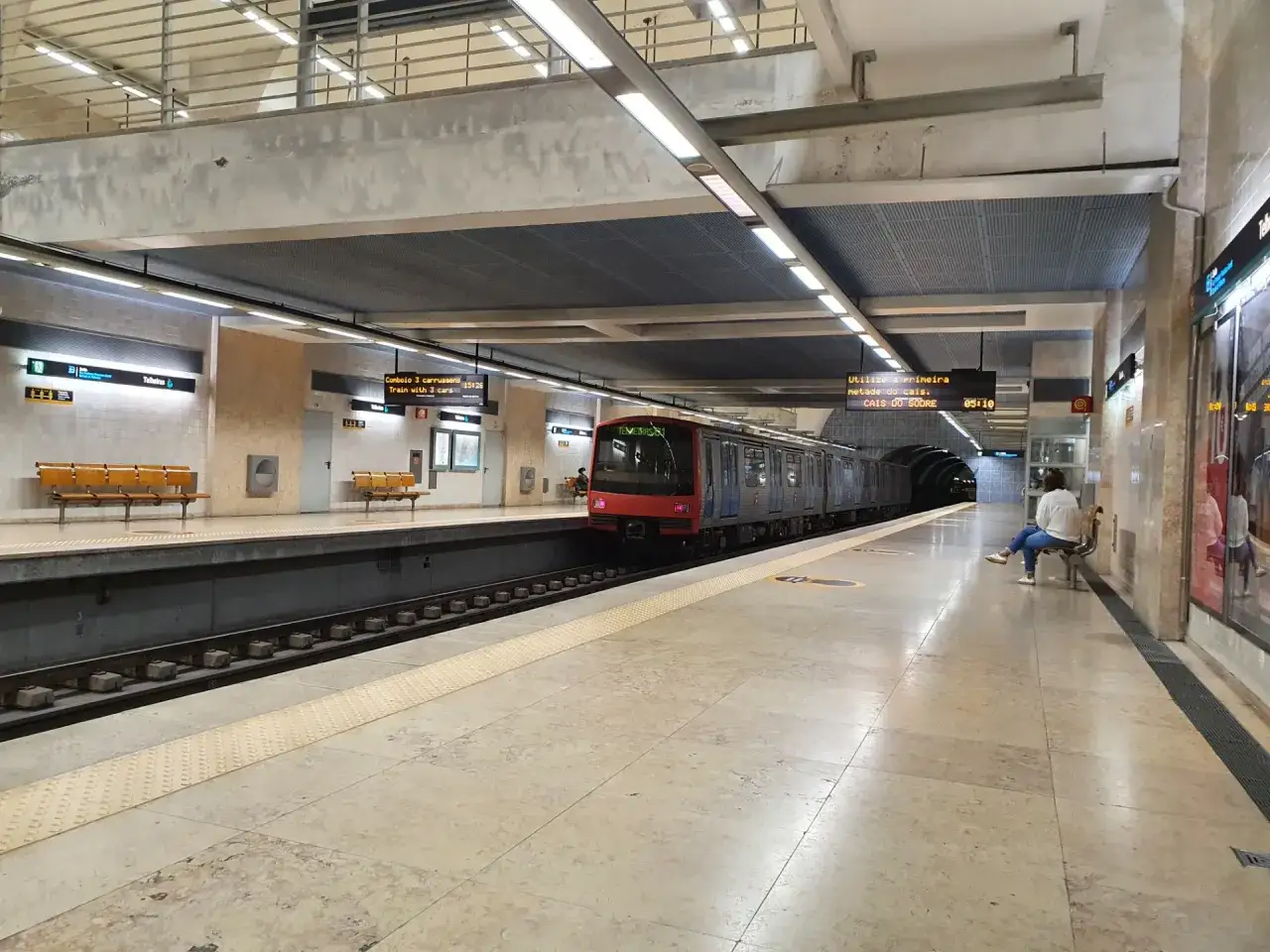 U-Bahn-Station am Lissabon Flughafen in die Stadt. Ein Zug f&auml;hrt ein, eine Frau wartet auf der Bank.