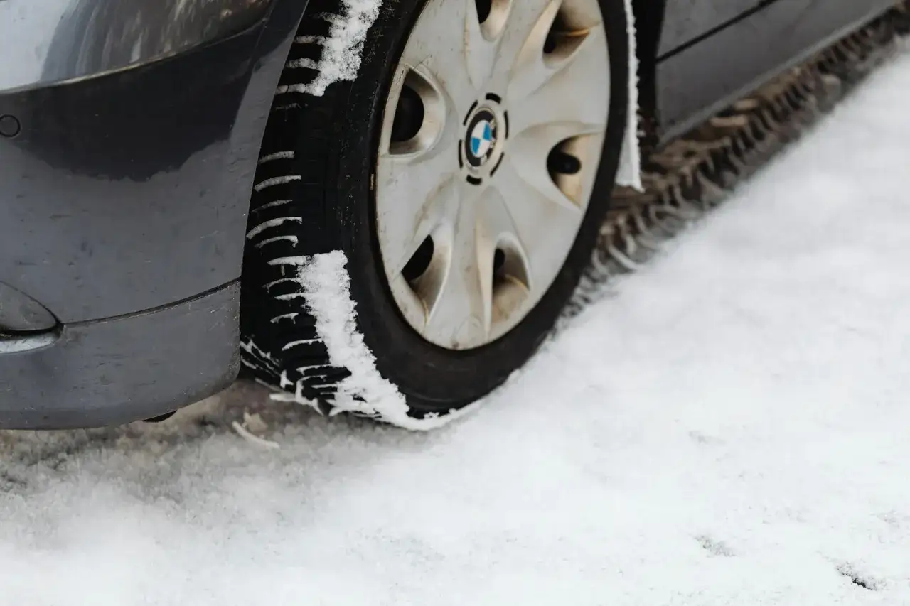 Koło samochodu BMW na śniegu, opony z bieżnikiem pokrytym śniegiem, jakby po przejechaniu przez kamień ognia (firestone).