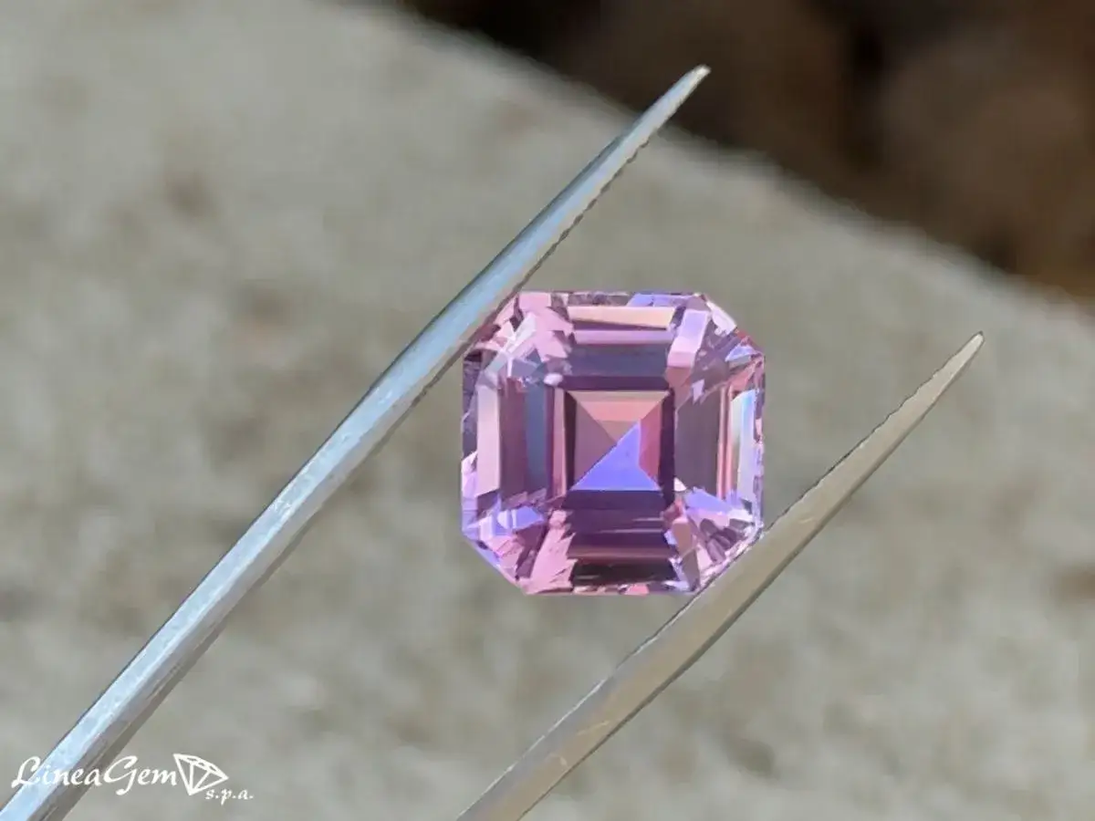 Una splendida kunzite rosa sfaccettata, tenuta da pinzette, mostra le sue vibranti propriet&agrave; cromatiche.