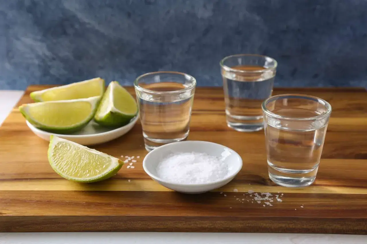 Tequila Sierra, jak pić? Kieliszki z tequilą, limonka i s&oacute;l na drewnianej desce. Idealny zestaw na wiecz&oacute;r.