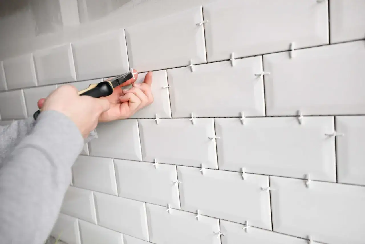 Pose d'un croisillon pour garantir la taille parfaite des joints de carrelage blanc.