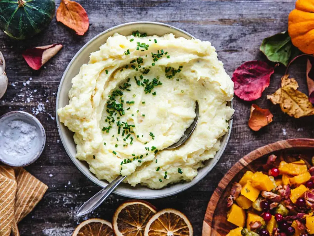 Krämigt potatismos, perfekt för ett höstligt potatismos recept, toppat med gräslök. Bredvid syns en skål med rostade grönsaker.