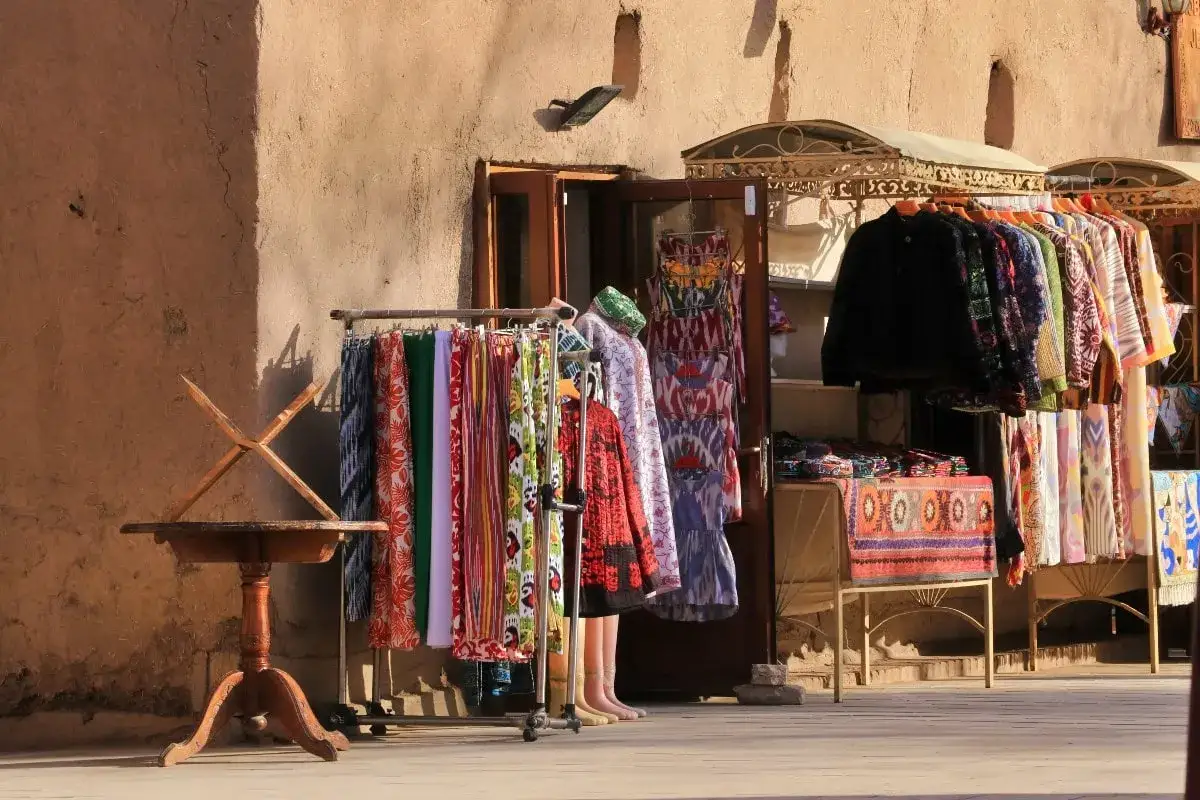 Kolorowe tkaniny i ubrania na straganie w Uzbekistanie. Czy jest bezpiecznie? Tak, podróżowanie po Uzbekistanie jest bezpieczne, a lokalni sprzedawcy są przyjaźni.